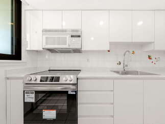 This modern kitchen boasts sleek white cabinetry and a gleaming stainless steel range, perfect for any home chef.