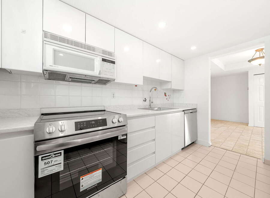 This modern kitchen boasts sleek white cabinetry and a matching tiled backsplash, creating a bright and airy atmosphere.
