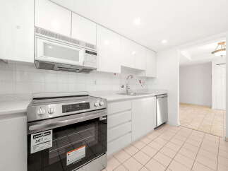 This modern kitchen boasts sleek white cabinetry and a matching tiled backsplash, creating a bright and airy atmosphere.