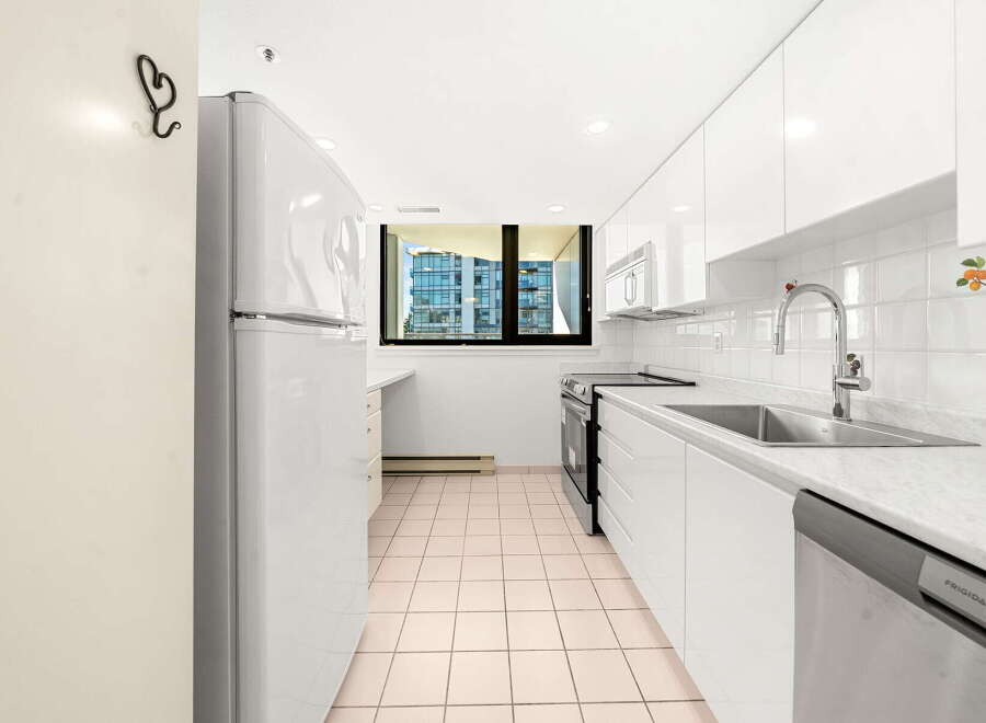 This bright and modern kitchen features sleek white cabinetry and a marble countertop, offering a clean and sophisticated look.