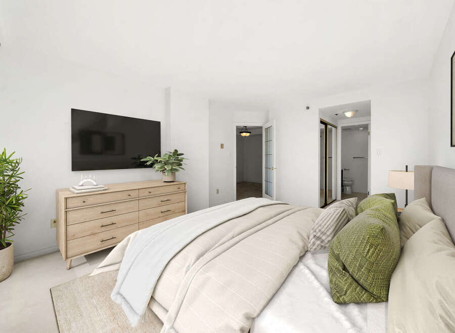 This beautifully appointed bedroom features a large flat-screen TV mounted above a modern wooden dresser, offering both entertainment and ample storage.