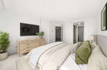 This beautifully appointed bedroom features a large flat-screen TV mounted above a modern wooden dresser, offering both entertainment and ample storage.