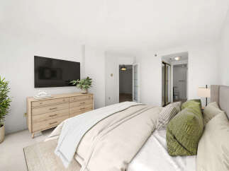 This beautifully appointed bedroom features a large flat-screen TV mounted above a modern wooden dresser, offering both entertainment and ample storage.