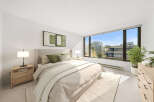 Experience modern living in this beautifully appointed bedroom, featuring a plush king-sized bed adorned with comfortable green and striped pillows.