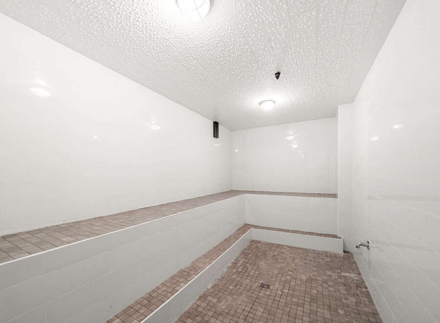 Experience ultimate relaxation in this pristine steam room, featuring tiered seating perfect for unwinding.