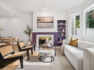 Step into this inviting living room, featuring a striking purple fireplace as the focal point, complemented by a modern abstract painting above.