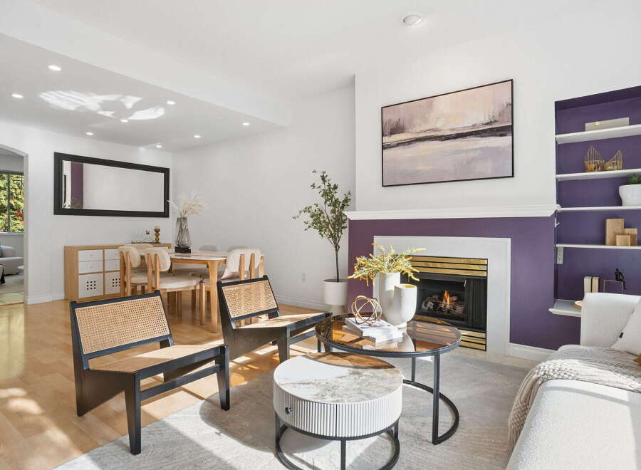 Step into this inviting living space, featuring a cozy fireplace with a striking purple accent wall and a modern abstract painting above.