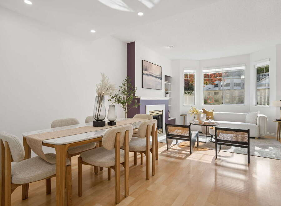 This beautifully staged dining and living area features a modern marble-topped dining table with upholstered chairs, complemented by a cozy living room with a plush white sofa and a stylish fireplace.