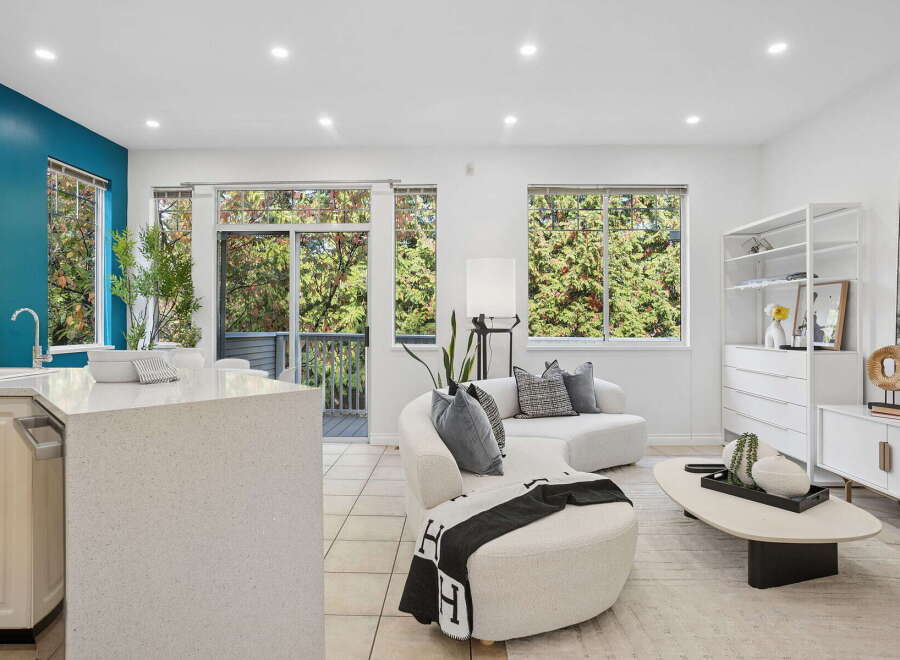 Experience modern living in this bright and airy open-concept space, featuring a sleek kitchen island and a comfortable living area.