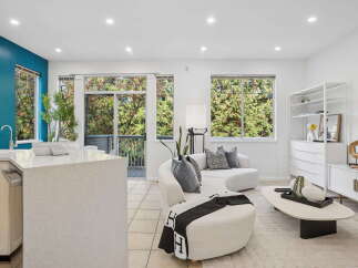 Experience modern living in this bright and airy open-concept space, featuring a sleek kitchen island and a comfortable living area.