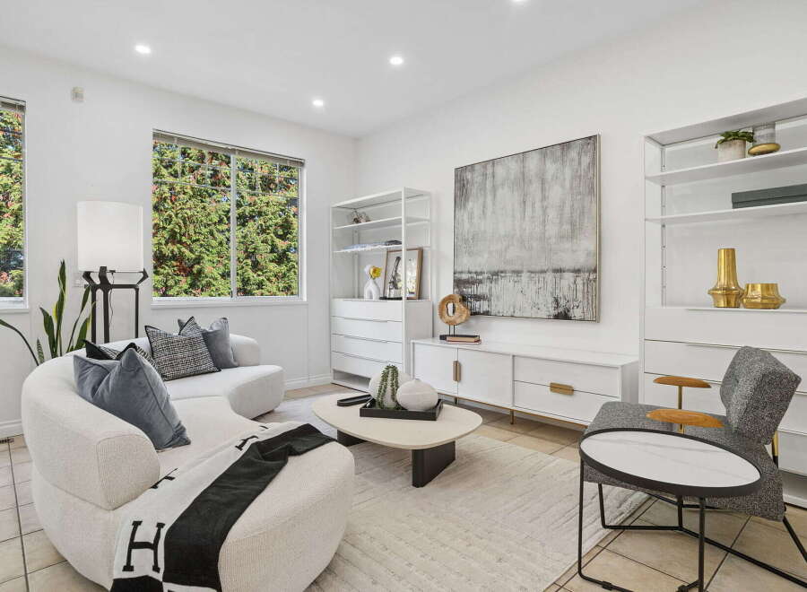 Step into this elegantly designed living room, featuring a plush, curved sofa adorned with decorative pillows and a chic throw blanket.