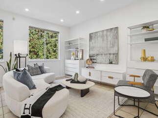 Step into this elegantly designed living room, featuring a plush, curved sofa adorned with decorative pillows and a chic throw blanket.