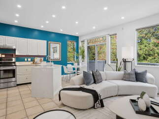 Experience modern living in this open-concept space featuring a sleek kitchen with white cabinetry and a stylish island, perfect for entertaining.