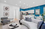 Experience modern living in this open-concept space, featuring a vibrant teal accent wall that beautifully complements the sleek white cabinetry of the kitchen.