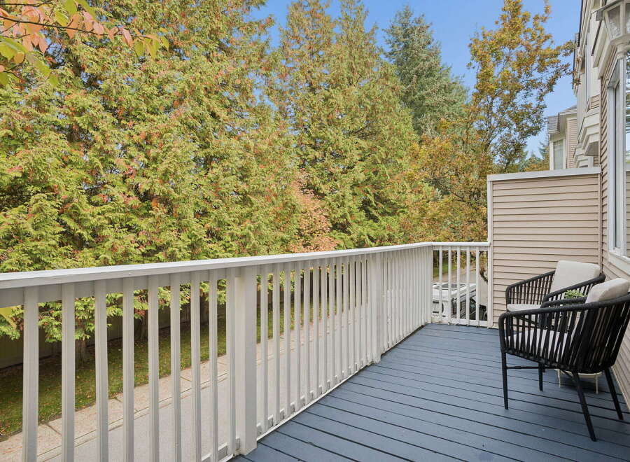 Enjoy your morning coffee on this charming balcony, offering a serene view of lush greenery and mature trees.