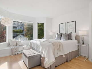 Bright and airy bedroom featuring a comfortable queen-size bed with plush pillows and a cozy throw blanket.