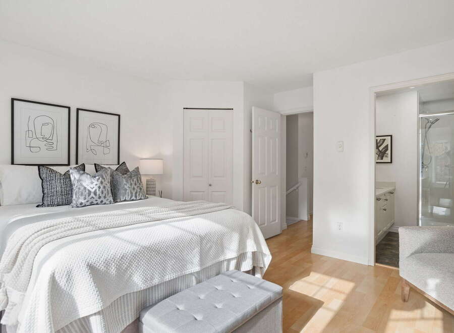 Step into this bright and airy bedroom, featuring a comfortable king-size bed adorned with plush pillows and a textured white comforter.