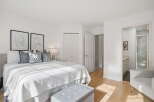 Step into this bright and airy bedroom, featuring a comfortable king-size bed adorned with plush pillows and a textured white comforter.