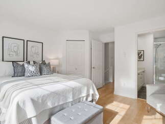 Step into this bright and airy bedroom, featuring a comfortable king-size bed adorned with plush pillows and a textured white comforter.