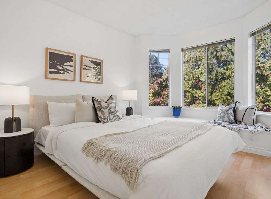 Experience serene living in this beautifully appointed bedroom, featuring a plush king-sized bed adorned with crisp white linens and a cozy knit throw.