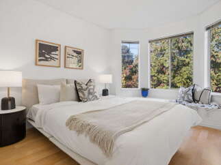 Experience serene living in this beautifully appointed bedroom, featuring a plush king-sized bed adorned with crisp white linens and a cozy knit throw.
