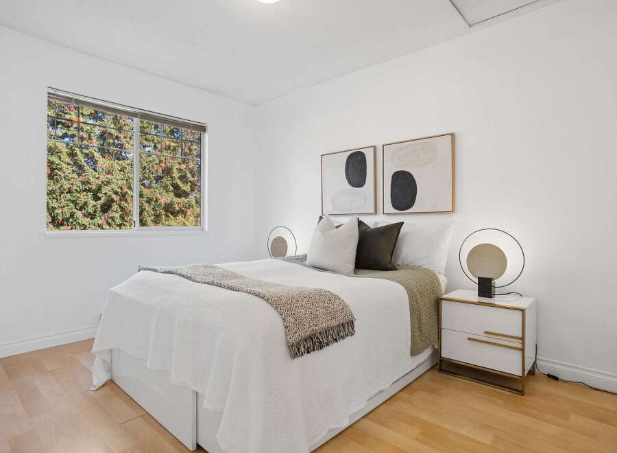This inviting bedroom features a comfortable queen-size bed adorned with crisp white linens and a textured throw blanket.