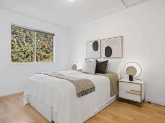 This inviting bedroom features a comfortable queen-size bed adorned with crisp white linens and a textured throw blanket.