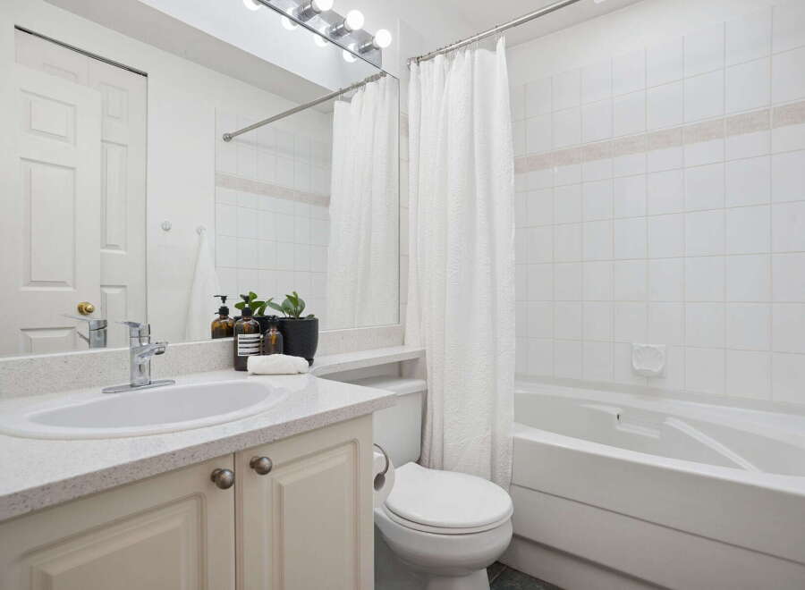This bright and airy bathroom features a spacious vanity with a speckled countertop and ample storage below.