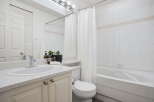 This bright and airy bathroom features a spacious vanity with a speckled countertop and ample storage below.