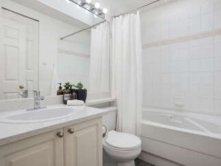 This bright and airy bathroom features a spacious vanity with a speckled countertop and ample storage below.