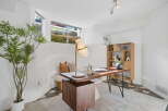 This home office features a stylish wooden desk with a modern lamp and a coffee maker, perfect for productivity.