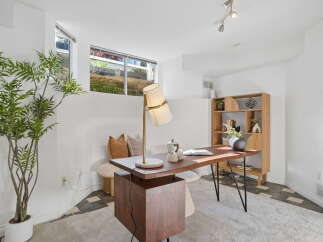 This home office features a stylish wooden desk with a modern lamp and a coffee maker, perfect for productivity.