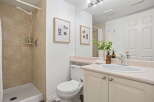 This charming bathroom features a modern shower with tiled walls and a convenient shower shelf.