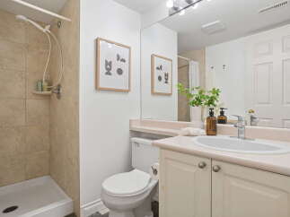 This charming bathroom features a modern shower with tiled walls and a convenient shower shelf.