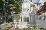 This charming townhouse features a welcoming entrance with a white picket fence and vibrant flower beds.