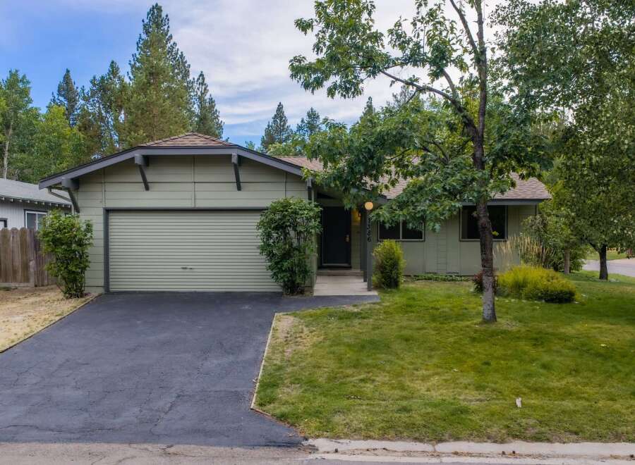 Charming single-story home with a light green exterior and a single-car garage.