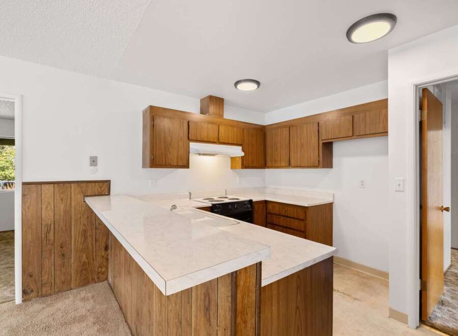 This charming kitchen features warm wooden cabinetry and a convenient breakfast bar with a speckled countertop.