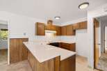This charming kitchen features warm wooden cabinetry and a convenient breakfast bar with a speckled countertop.
