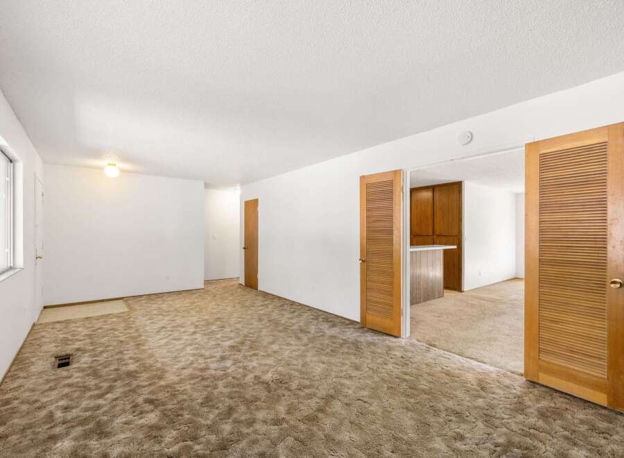 Step into a spacious living area featuring plush, neutral-toned carpeting that extends throughout the room, creating a warm and inviting atmosphere.