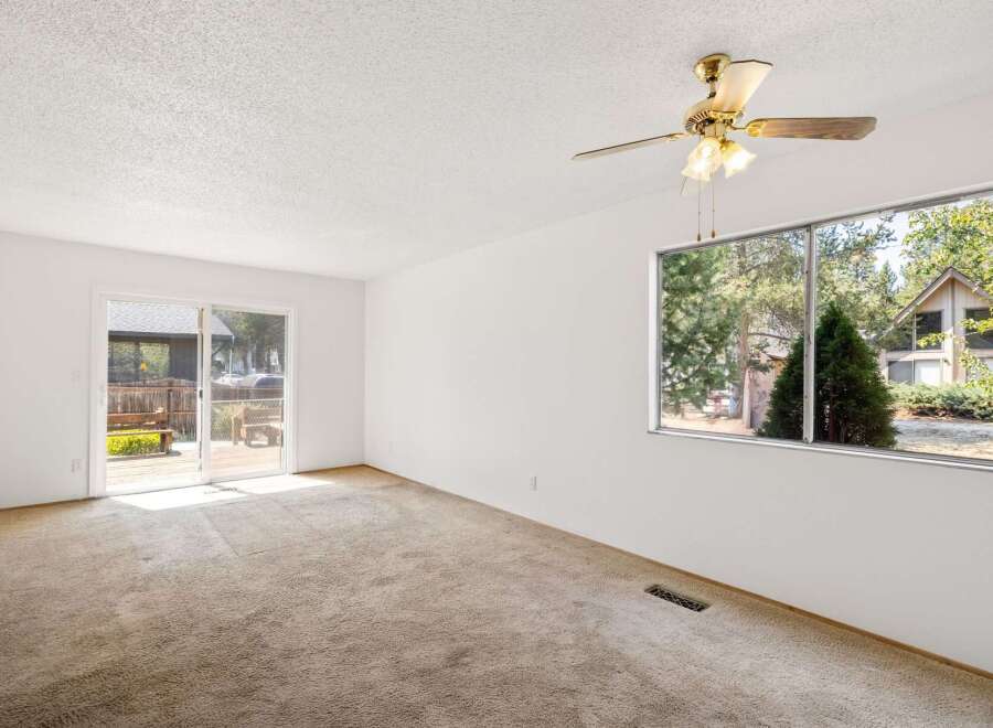 This spacious room features a large sliding glass door that opens to an outdoor deck, perfect for enjoying the surrounding nature.