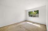 This spacious room features a large window offering ample natural light and a view of lush greenery.