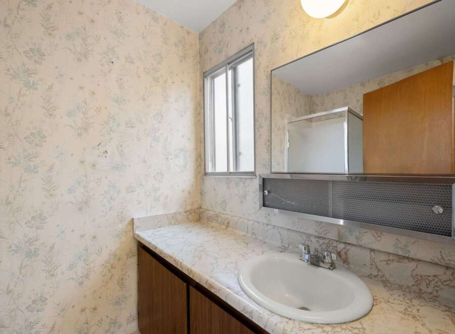 This bathroom features a charming floral wallpaper that adds a touch of vintage appeal.