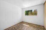 This empty room features a large window offering a view of lush green trees, bringing natural light and a sense of tranquility indoors.