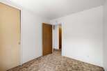 This unfurnished bedroom features a large closet with a sliding door and a wooden interior door that opens to a hallway.
