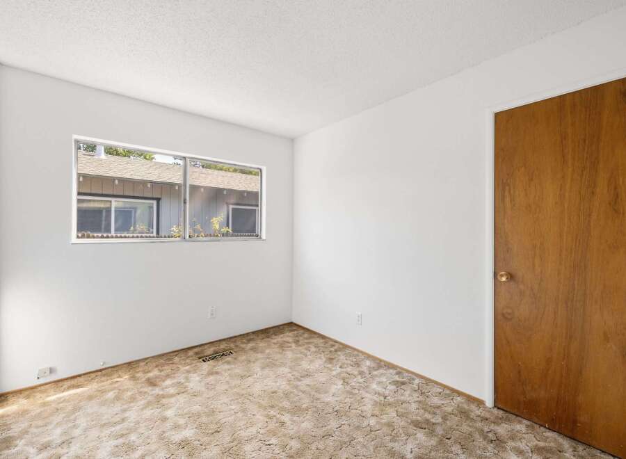 This room features a large window offering a view of the exterior and a classic wooden door with a brass knob.