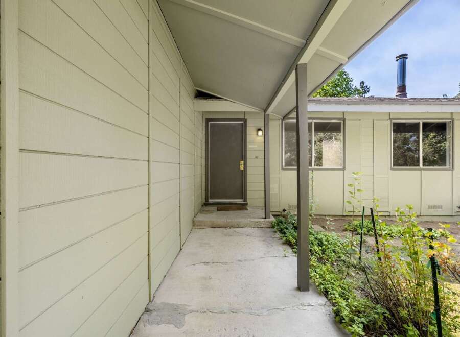Discover the inviting entrance to this charming home, featuring a covered walkway leading to a welcoming front door.