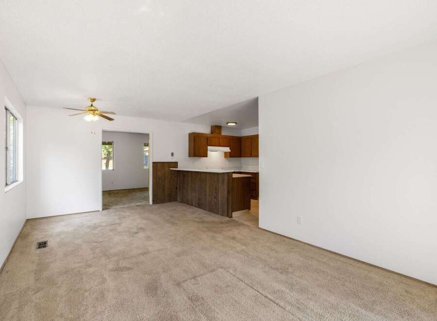Step into this inviting living space featuring plush carpeting and a ceiling fan for year-round comfort.