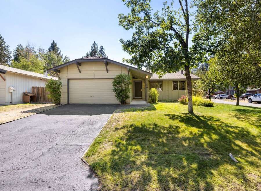 This charming single-family home features a light beige exterior with a matching garage door and a dark gray roof.