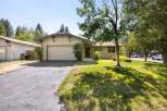 This charming single-family home features a light beige exterior with a matching garage door and a dark gray roof.