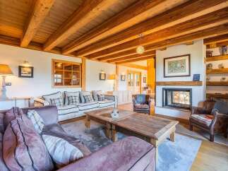 Experience rustic charm in this inviting living room, featuring a stunning stone fireplace and exposed wooden beams that create a warm, cozy atmosphere.